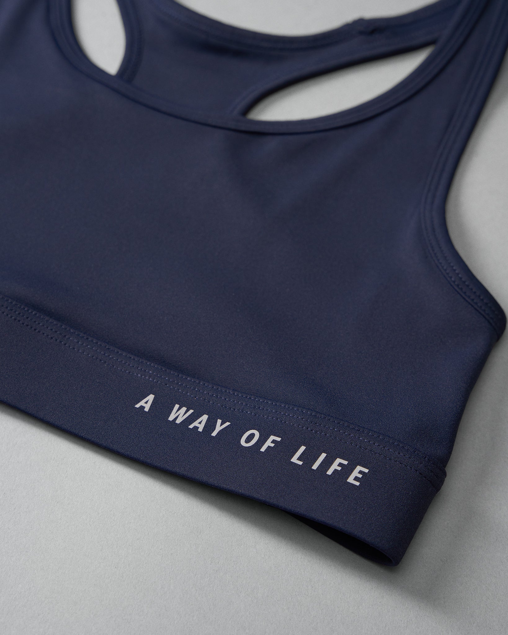 Navy blue sports bra with 'A Way of Life' text on a light gray background