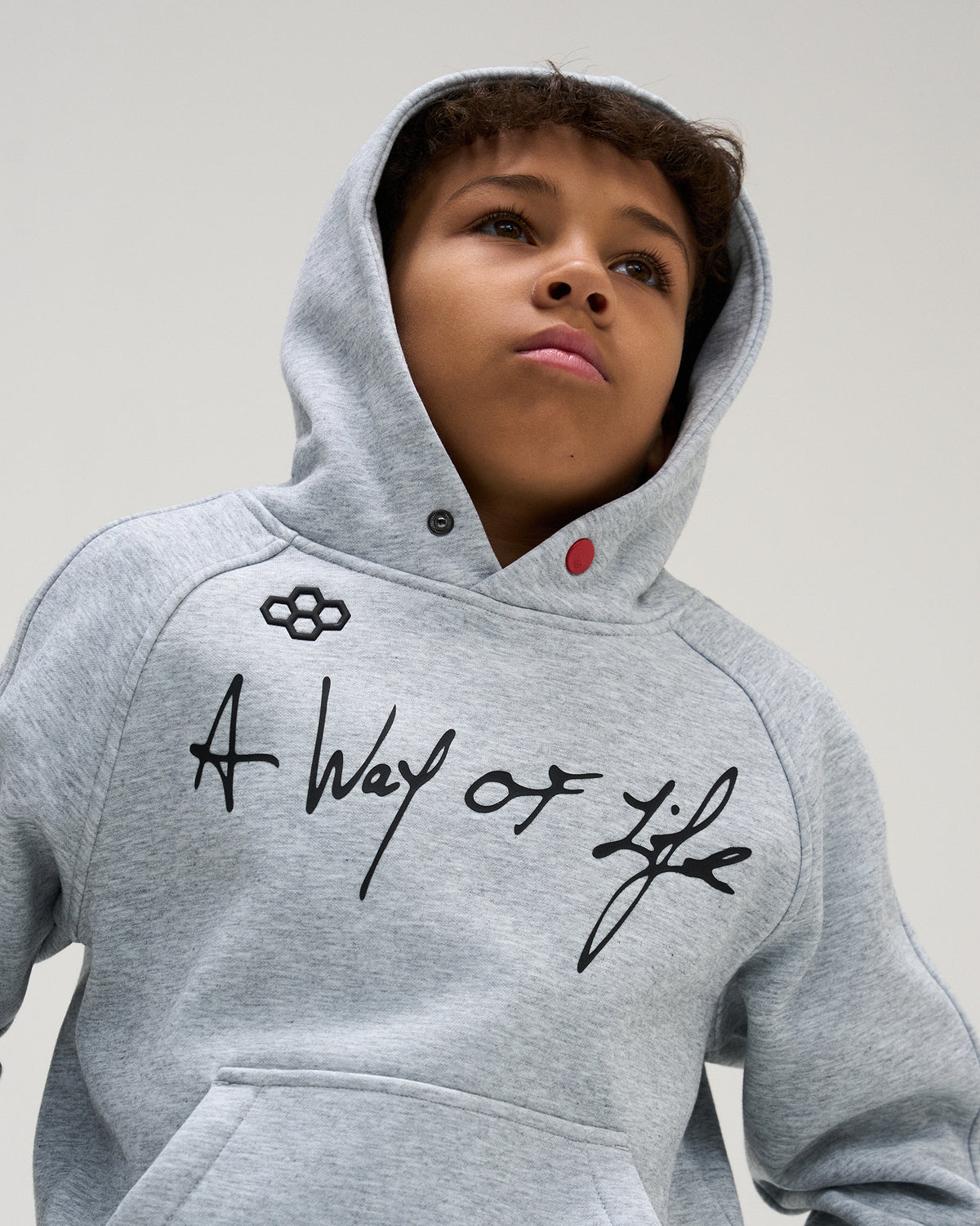 Close-up of the RUDIS A Way of Life Youth Tech Fleece Hoodie in Heather Gray, highlighting the script chest graphic, RUDIS logo, hood, and snap detail.