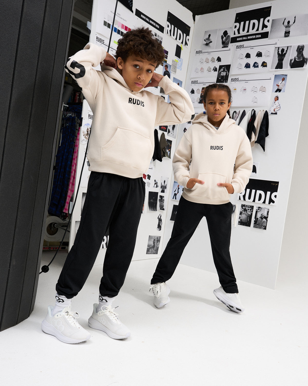 Two youth athletes model the RUDIS Wrestling Youth Relaxed Comfort Fleece Hoodie in Bone, featuring a RUDIS chest logo, kangaroo pocket, and relaxed fit.