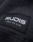 A close-up of a black clothing label featuring the brand name RUDIS and the phrase A WAY OF LIFE in white text set against a textured fabric background