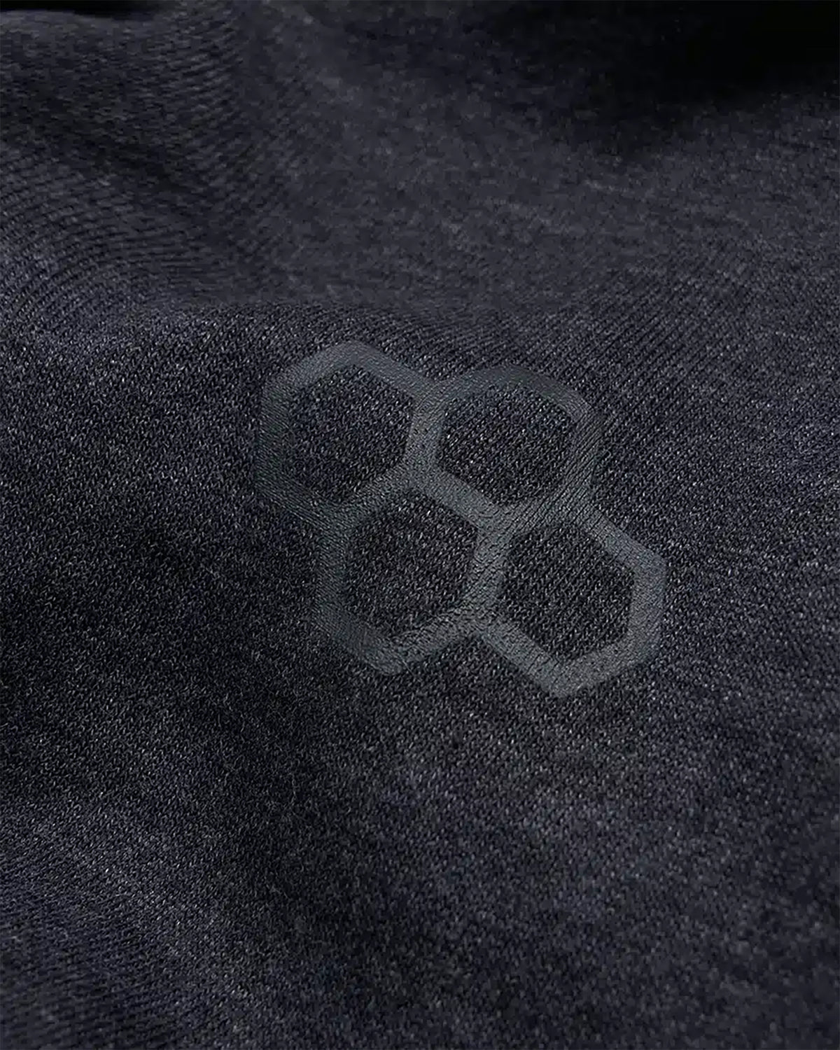 A close-up view of black fabric featuring a subtle hexagonal pattern highlighting texture and design details