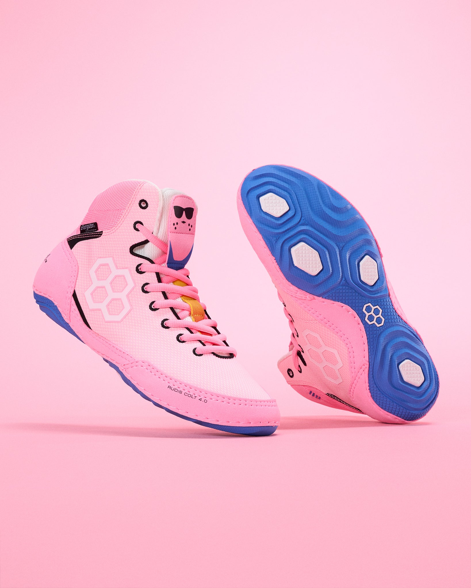 Pink wrestling shoe with blue soles on a pink background