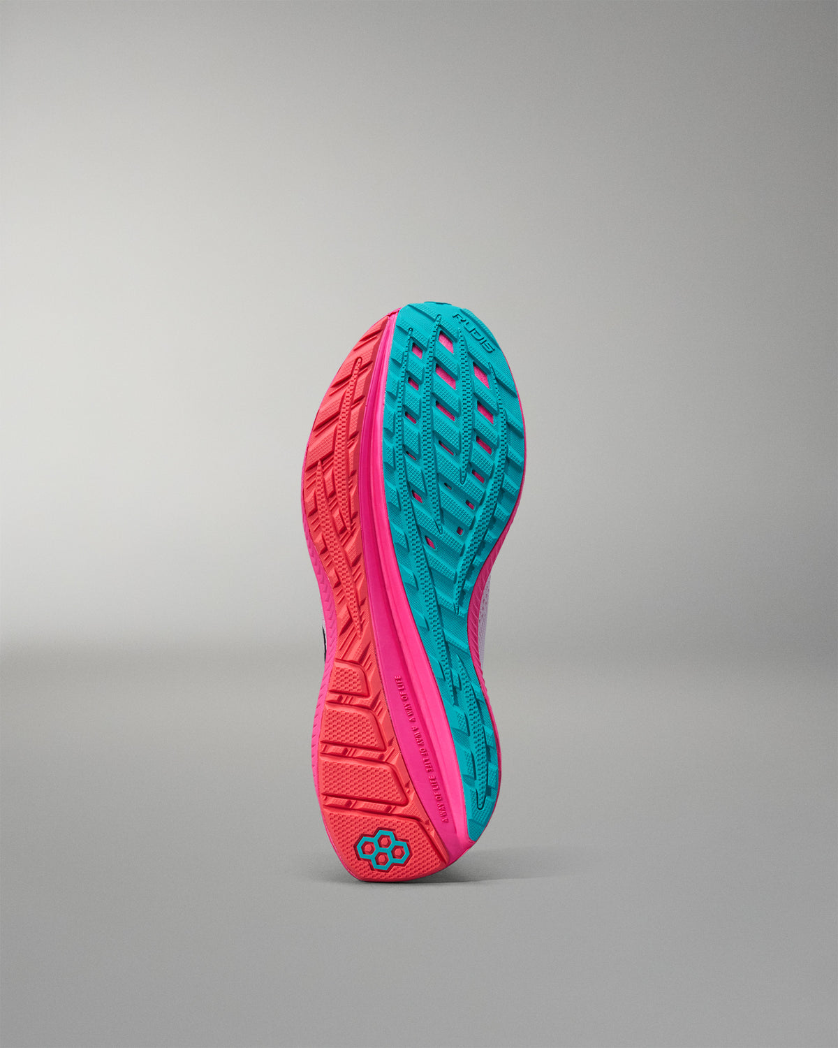 Close-up of a pink and teal athletic shoe sole on a gray background