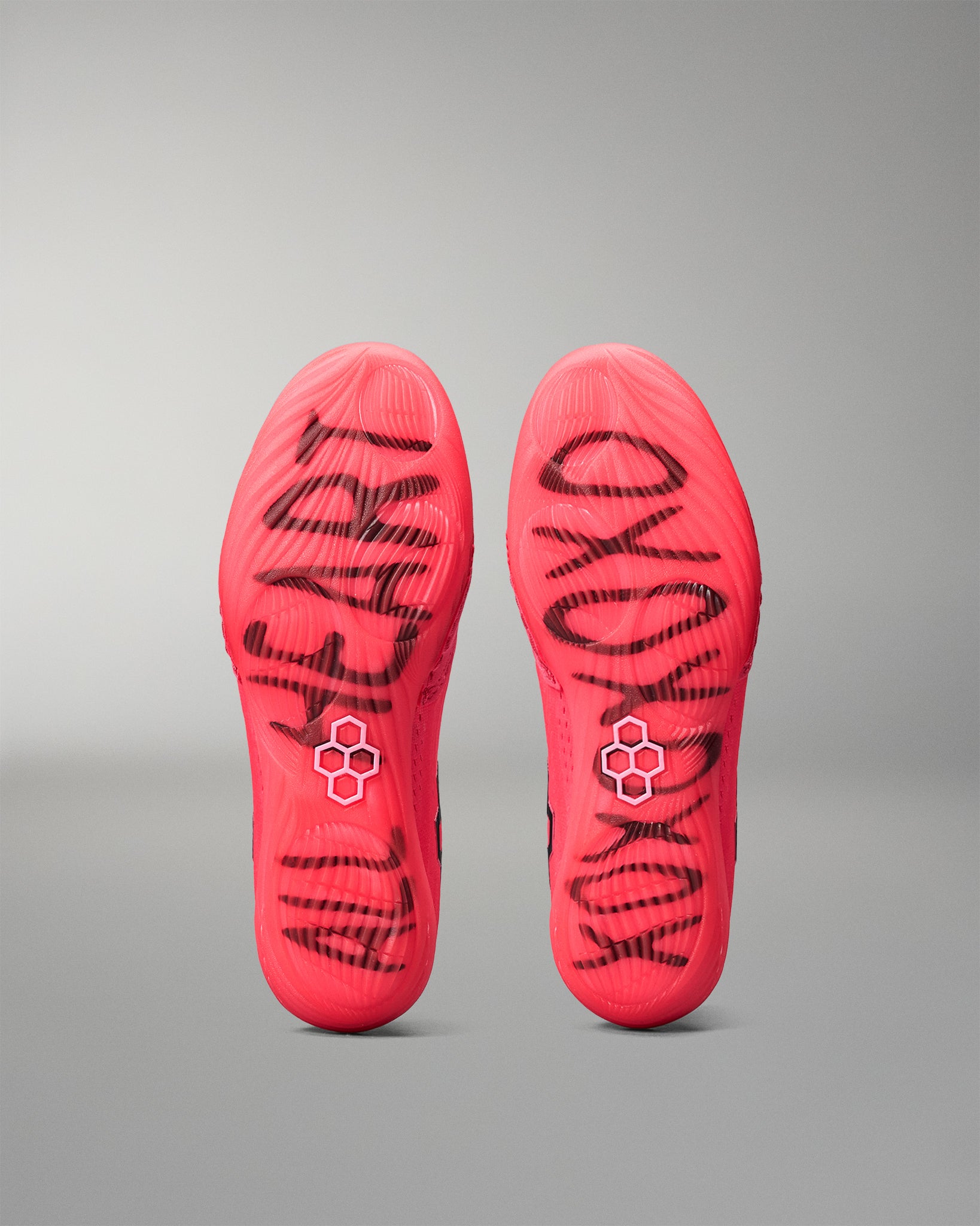 Red wrestling shoes with black branding on a gray background