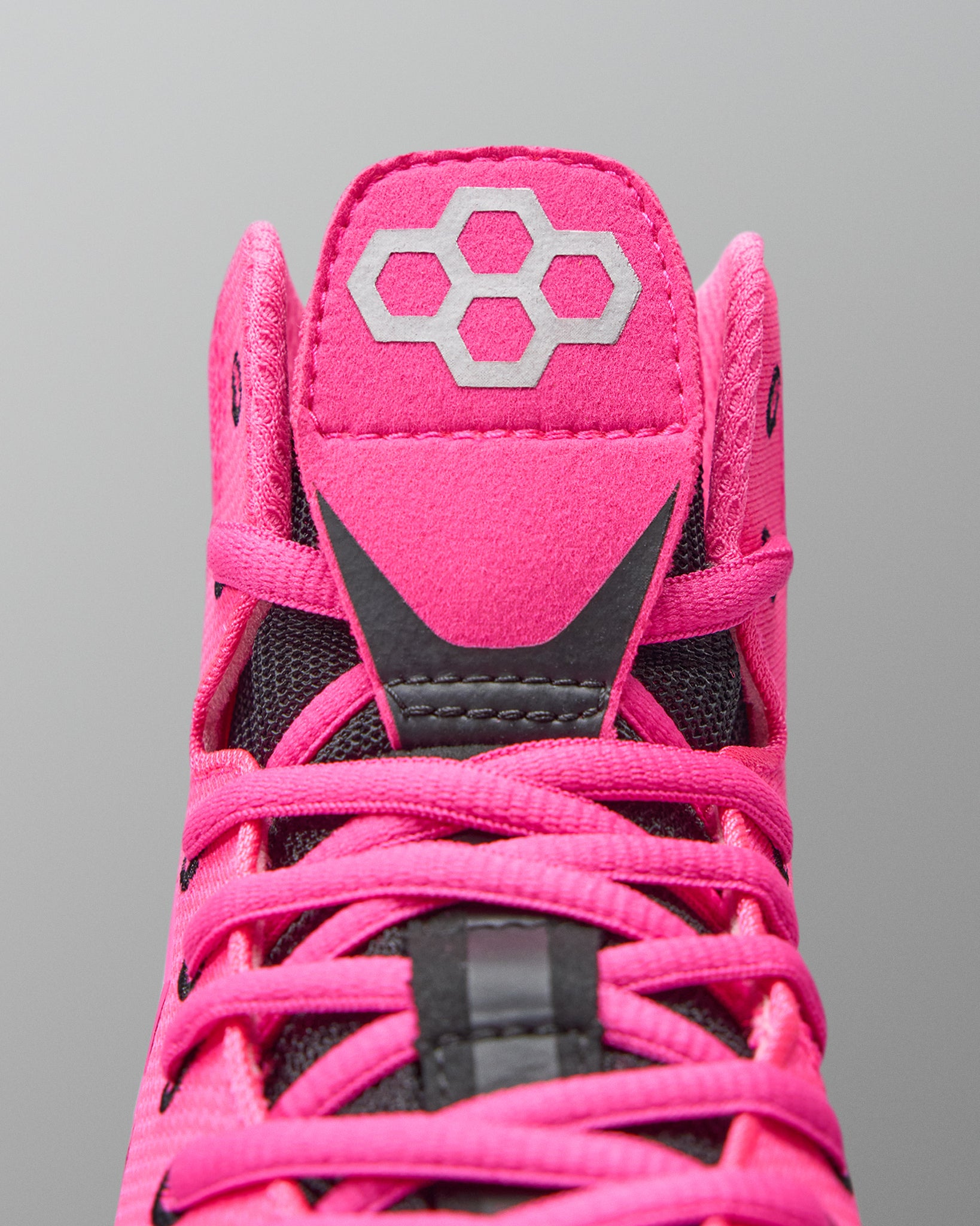 Close-up of a pink sports shoe with a brand logo on a gray background