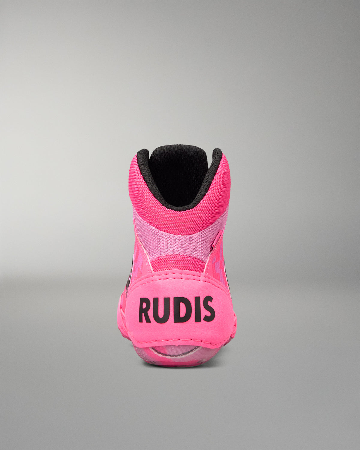 A single high-top Wrestling shoe shown from the back, featuring a vibrant pink upper with a black collar, black 'RUDIS' branding on the heel, and a black interior lining, set against a neutral gray studio background.