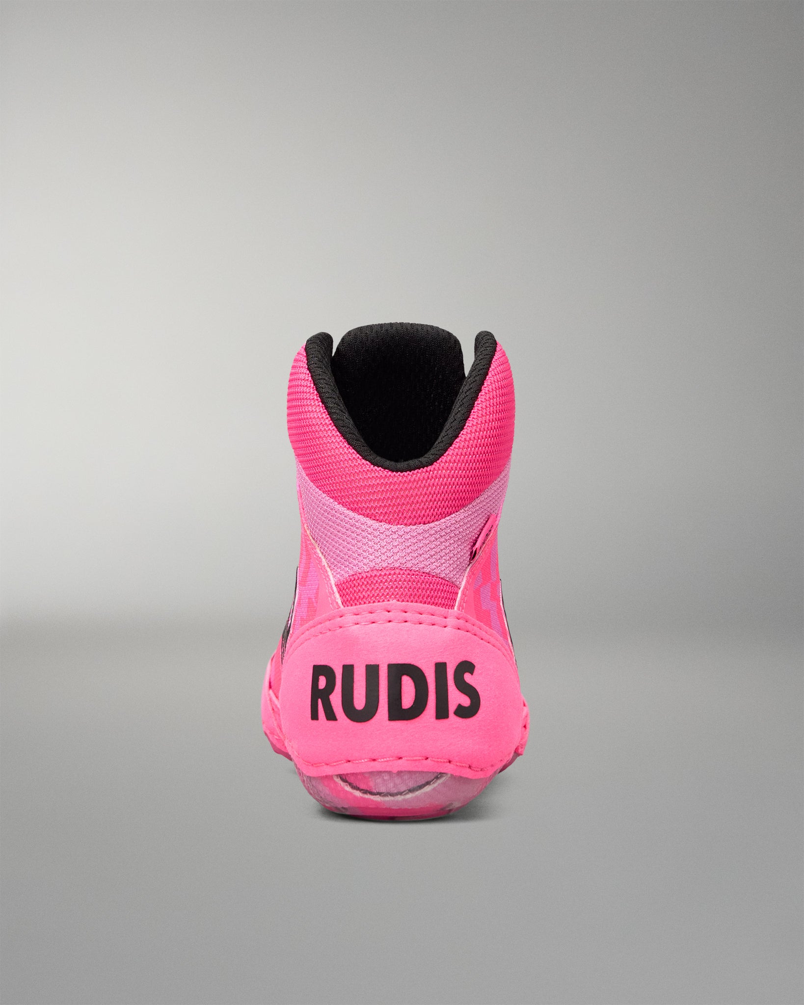 A single high-top Wrestling shoe shown from the back, featuring a vibrant pink upper with a black collar, black 'RUDIS' branding on the heel, and a black interior lining, set against a neutral gray studio background.