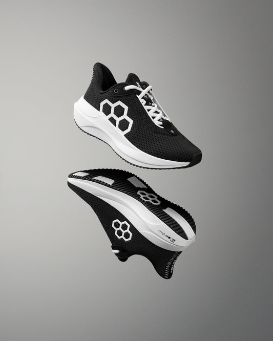 Black and white athletic shoe with brand logo on a gray background