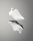 White athletic shoe with brand logo on a reflective gray surface
