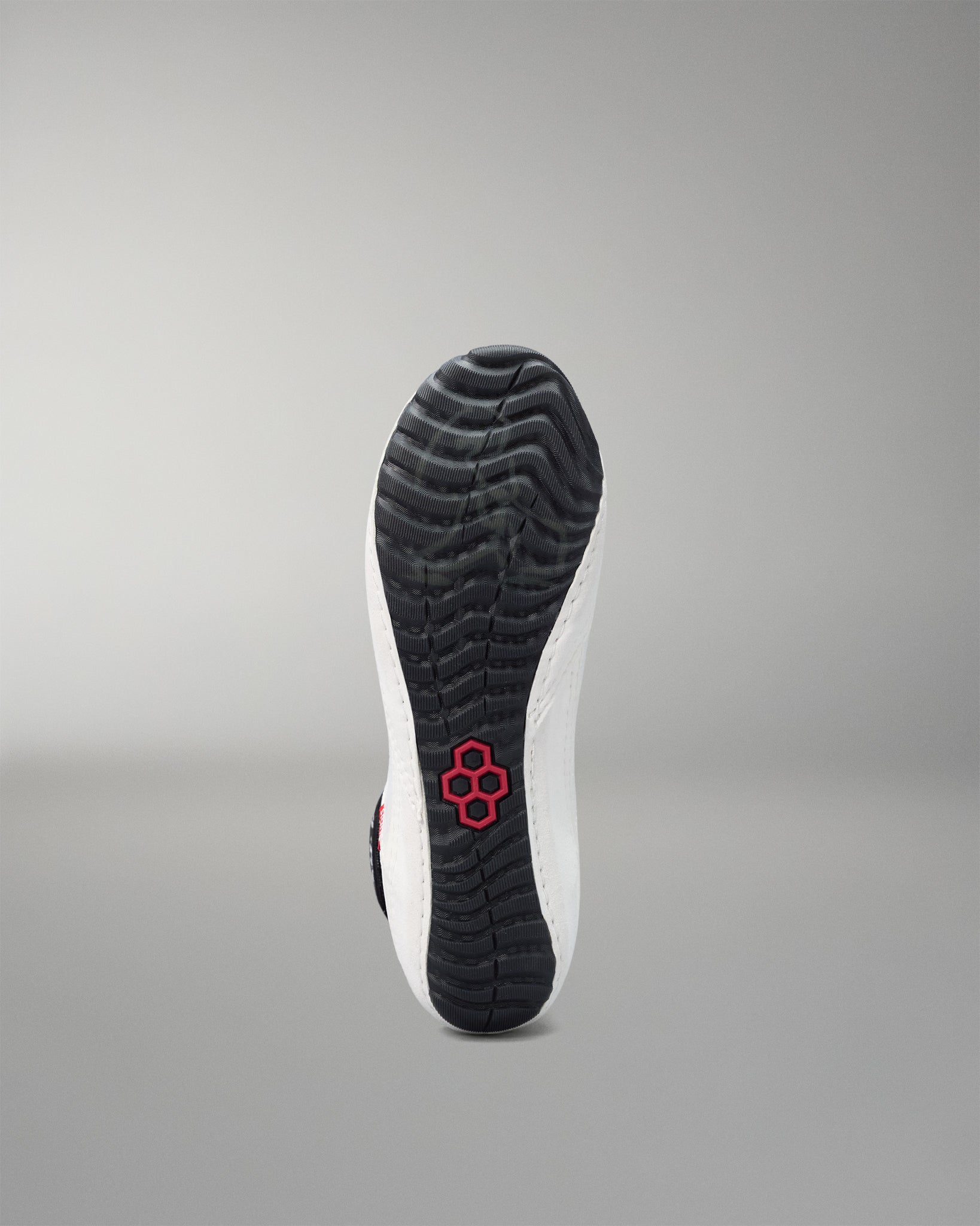 Sole of a wrestling shoe with a red logo on a gray background