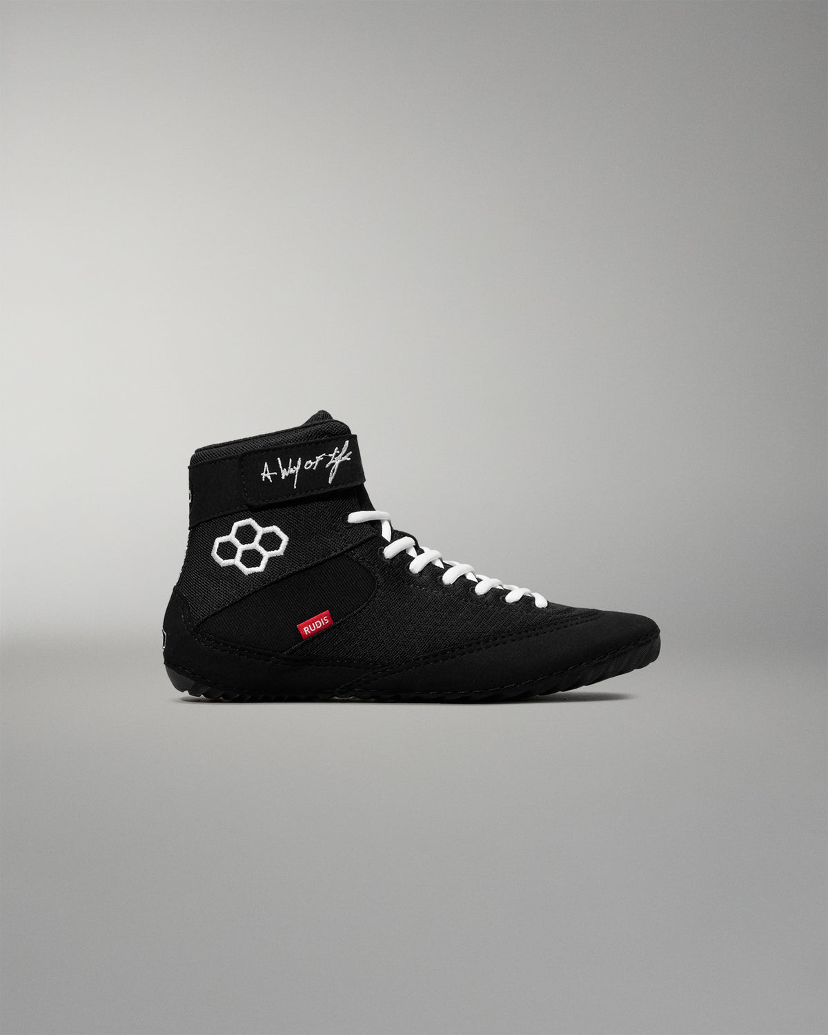 Black wrestling shoe with white laces on a gray background