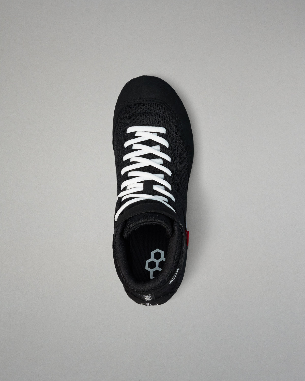 Black wrestling shoe with white laces on a gray background