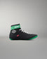 Black and green wrestling shoe with white laces on a gray background