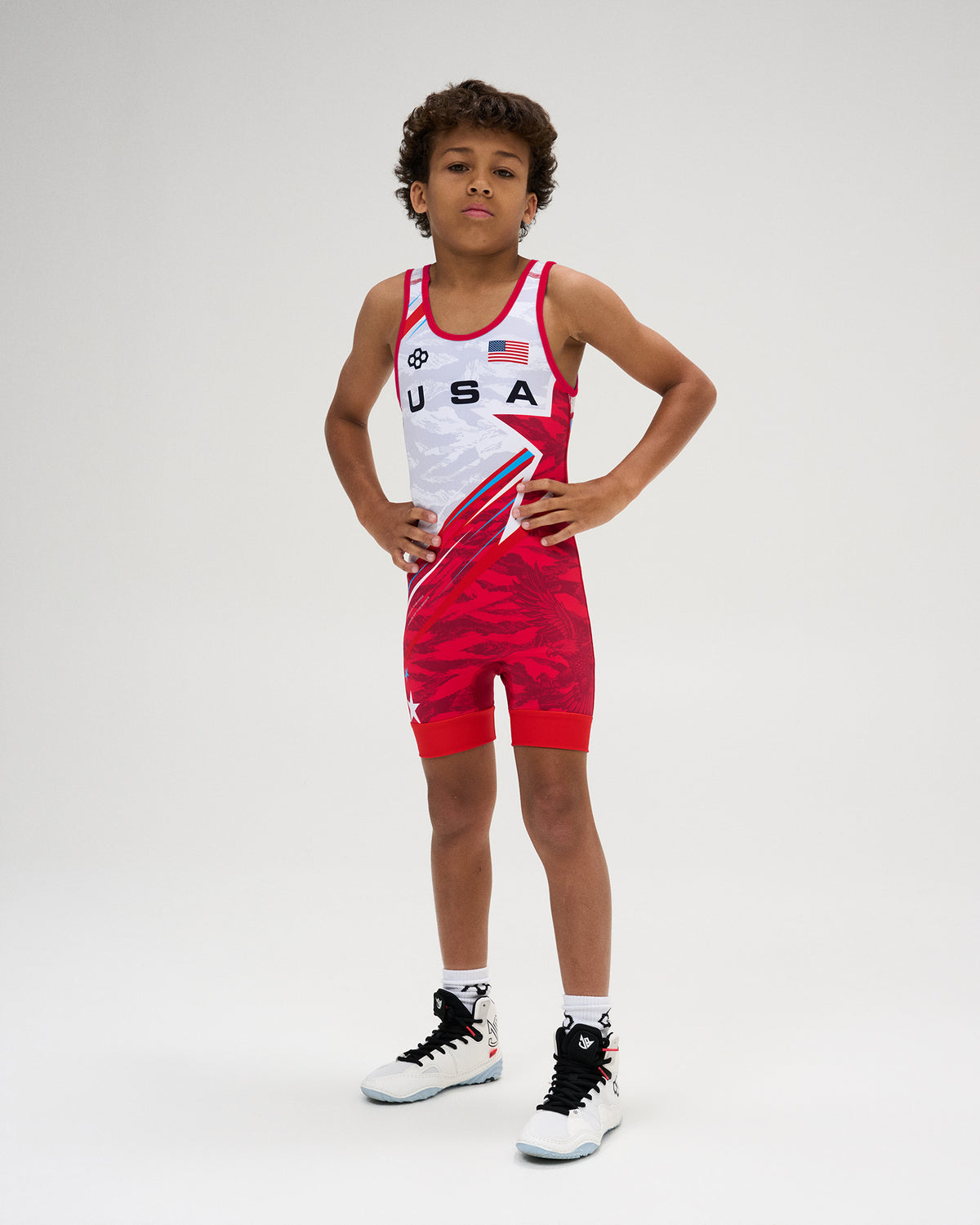 USA Wrestling Shooting Star Youth Elite 2.0 Singlet in red and white, featuring USA and American flag graphics, RUDIS branding, and a bold red shooting-star design.