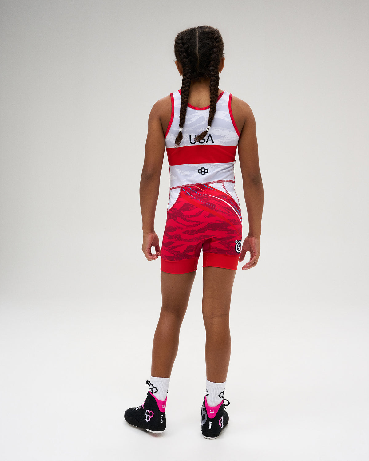 Back view of the USA Wrestling Shooting Star Girls’ Elite 2.0 Singlet in red and white, featuring USA detailing, RUDIS Hex branding, and a dynamic red graphic pattern.