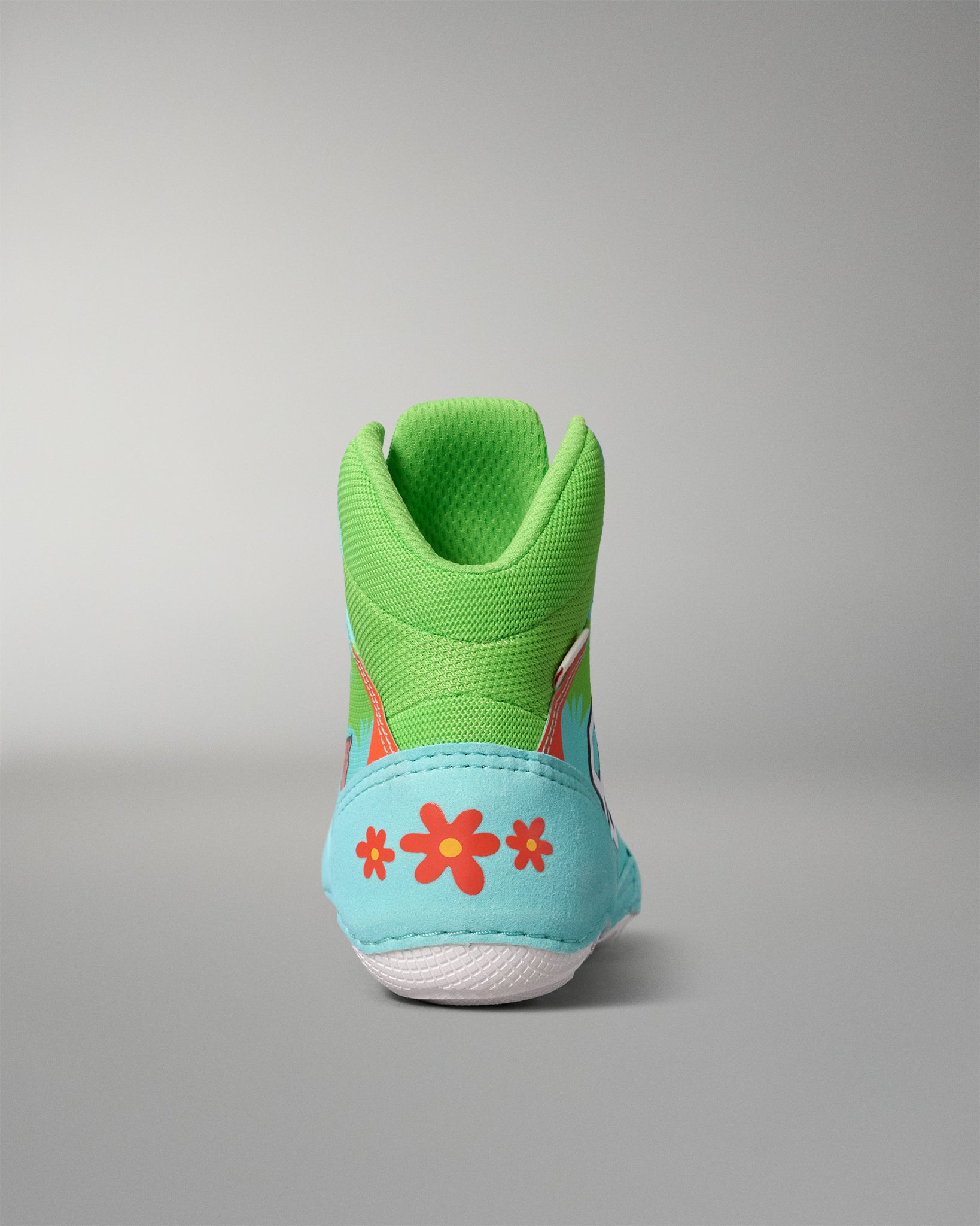 Rear view of the RUDIS Scooby-Doo Colt 4.0 youth wrestling shoe featuring a green padded ankle collar, turquoise heel panel, orange flowers, and white outsole.
