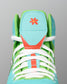 Close-up of the RUDIS Scooby-Doo Colt 4.0 youth wrestling shoe highlighting white laces, green mesh panels, turquoise tongue, and orange flower graphic.