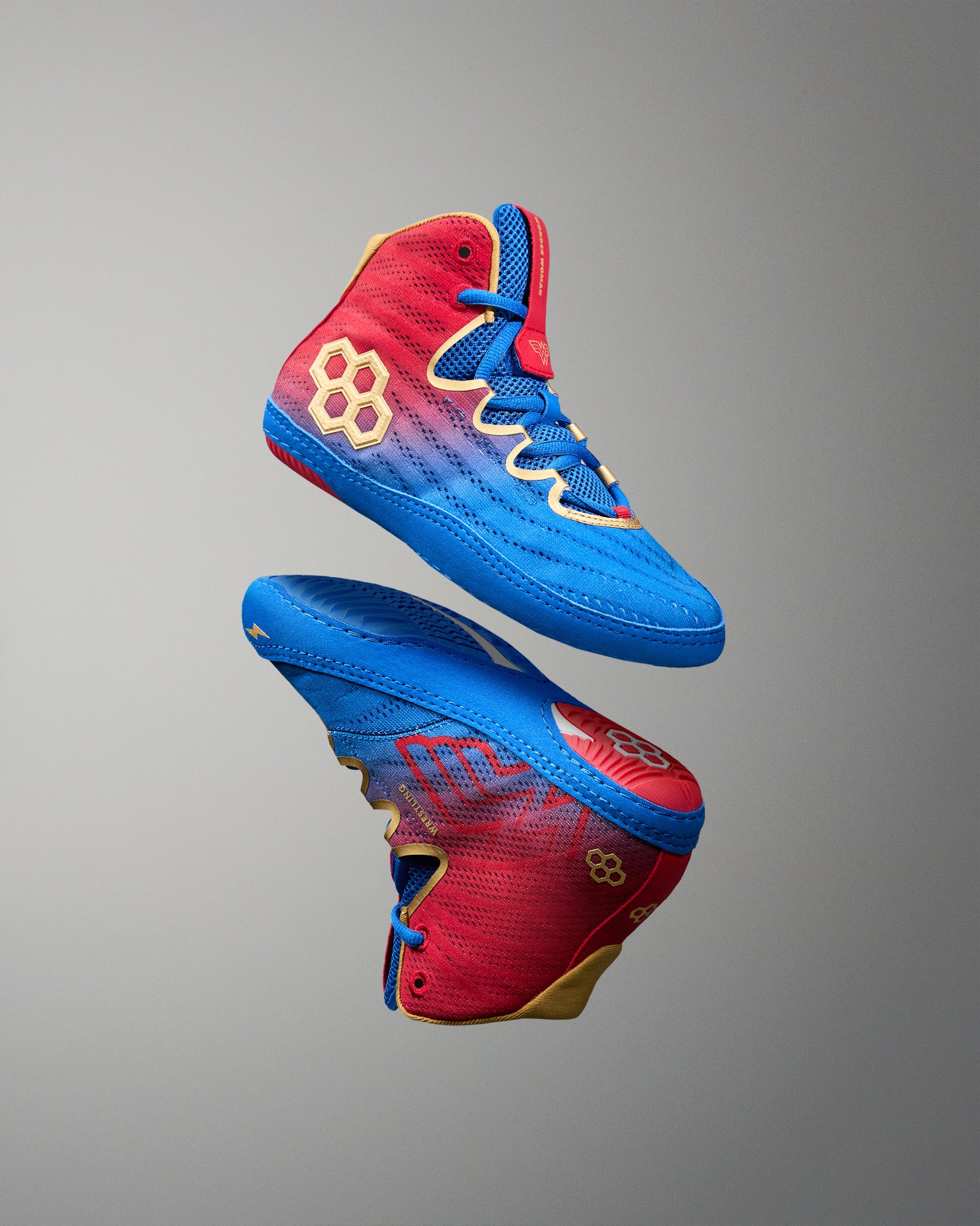 RUDIS Wonder Woman Hildebrandt 2.0 girls' wrestling shoes shown in an elevated display, highlighting blue and red uppers, gold RUDIS logos and Wonder Woman graphics.